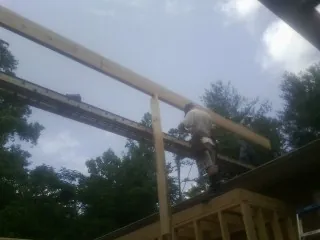 Carpenter setting a ridge beam over a new addition frame — Ice Dam Removal by Roofing Brothers in Alpha