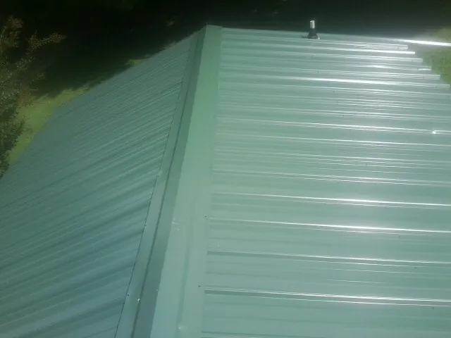New green metal panels meeting at the ridge of a roof — Flat Roof Repair work by our crew in Alpha