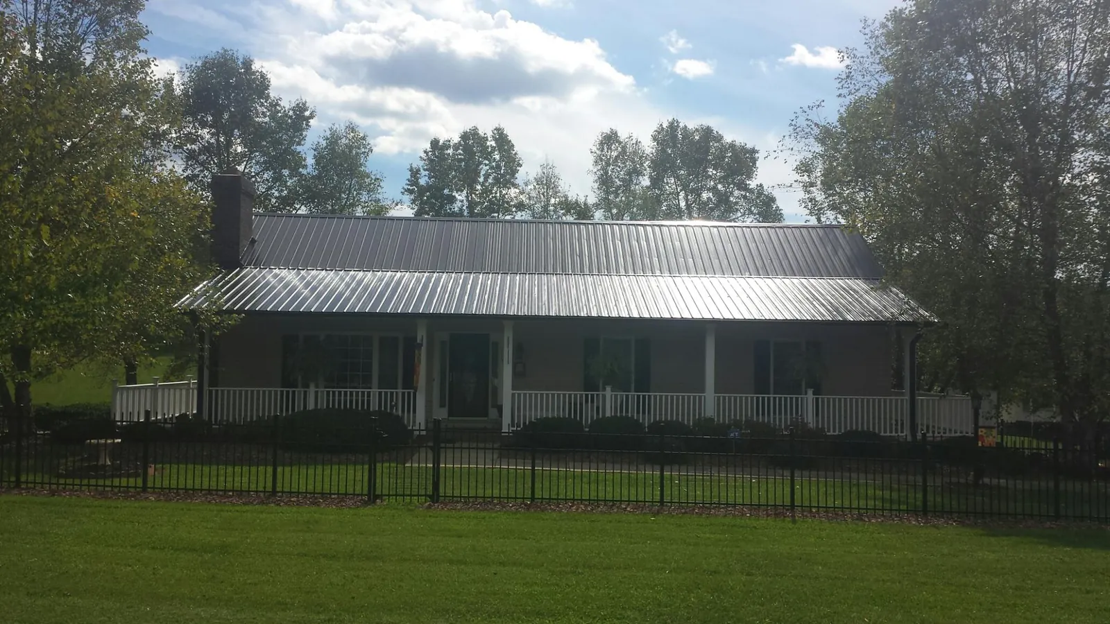 Gray metal roof on a brick ranch with a full width front porch — Gutter Guard Installation work by our crew in Alpha